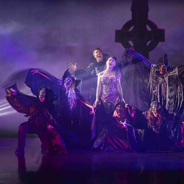 Dramatische Tanz der Vampire-Szene mit dunklen Kostümen, Masken und mystischer Friedhofskulisse.