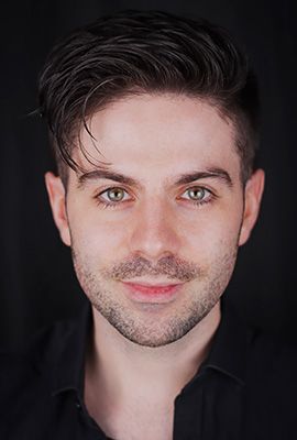 Das Portrait zeigt Chris Green mit kurzen, dunklen Haaren, grünlichen Augen und einem dezenten Lächeln.