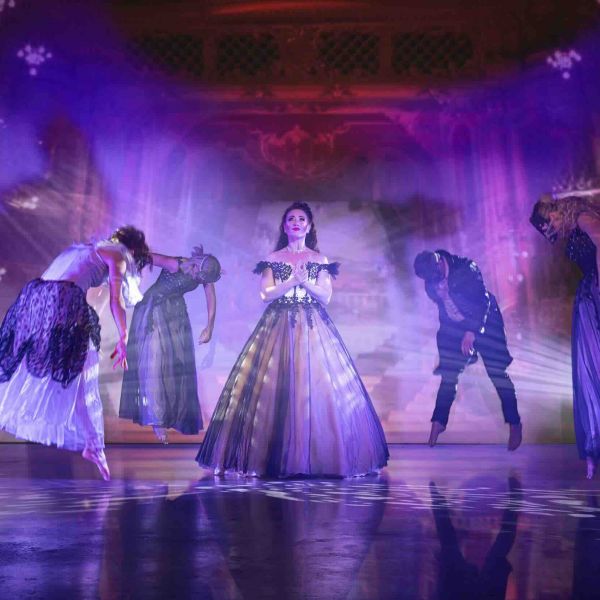 Eine eindrucksvolle Szene aus Elisabeth der Best of Musicals Show: Die Hauptfigur im prächtigen Ballkleid steht im Zentrum, umgeben von schwebenden Gestalten. Mystische Beleuchtung und schimmernde Effekte verstärken die dramatische Atmosphäre.