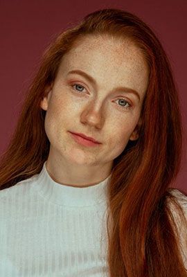 Das Portrait zeigt Jana Mayer mit zusammengebundenen braunen Haaren und hellen Augen. Sie blickt ruhig in die Kamera und lächelt dezent.